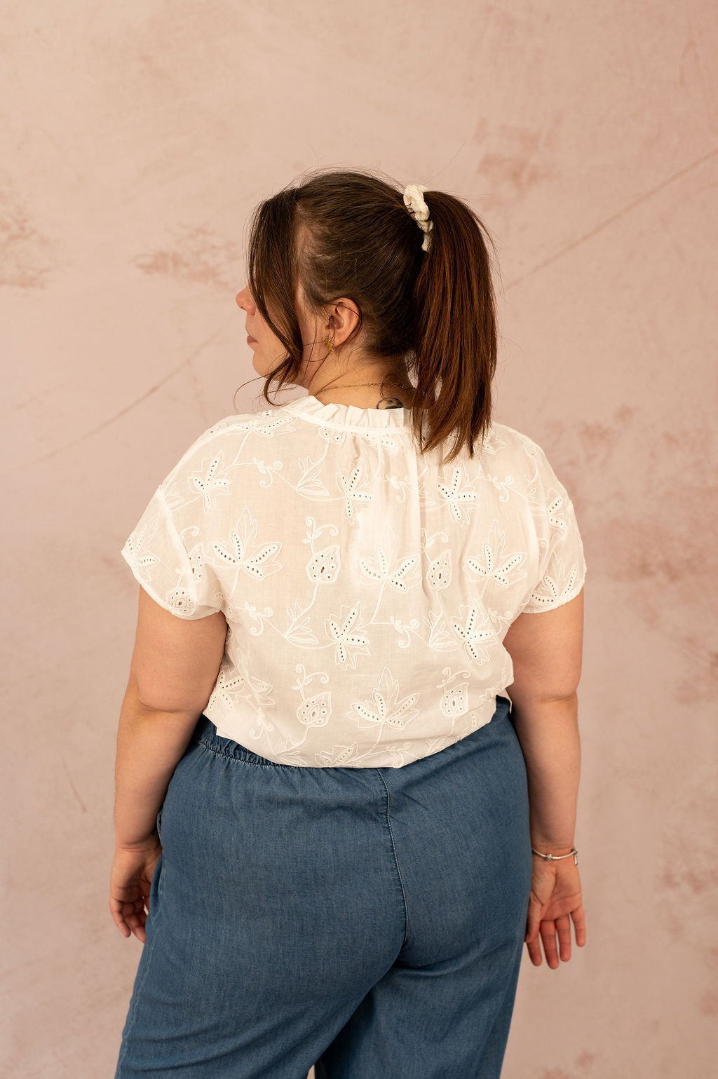 Femme de dos portant la blouse Camilla en broderie anglaise, vue sur le détail du dos.