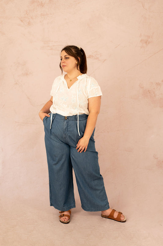 Femme plus size portant la blouse Camilla avec un pantalon large en jean, tenue grande taille estivale.