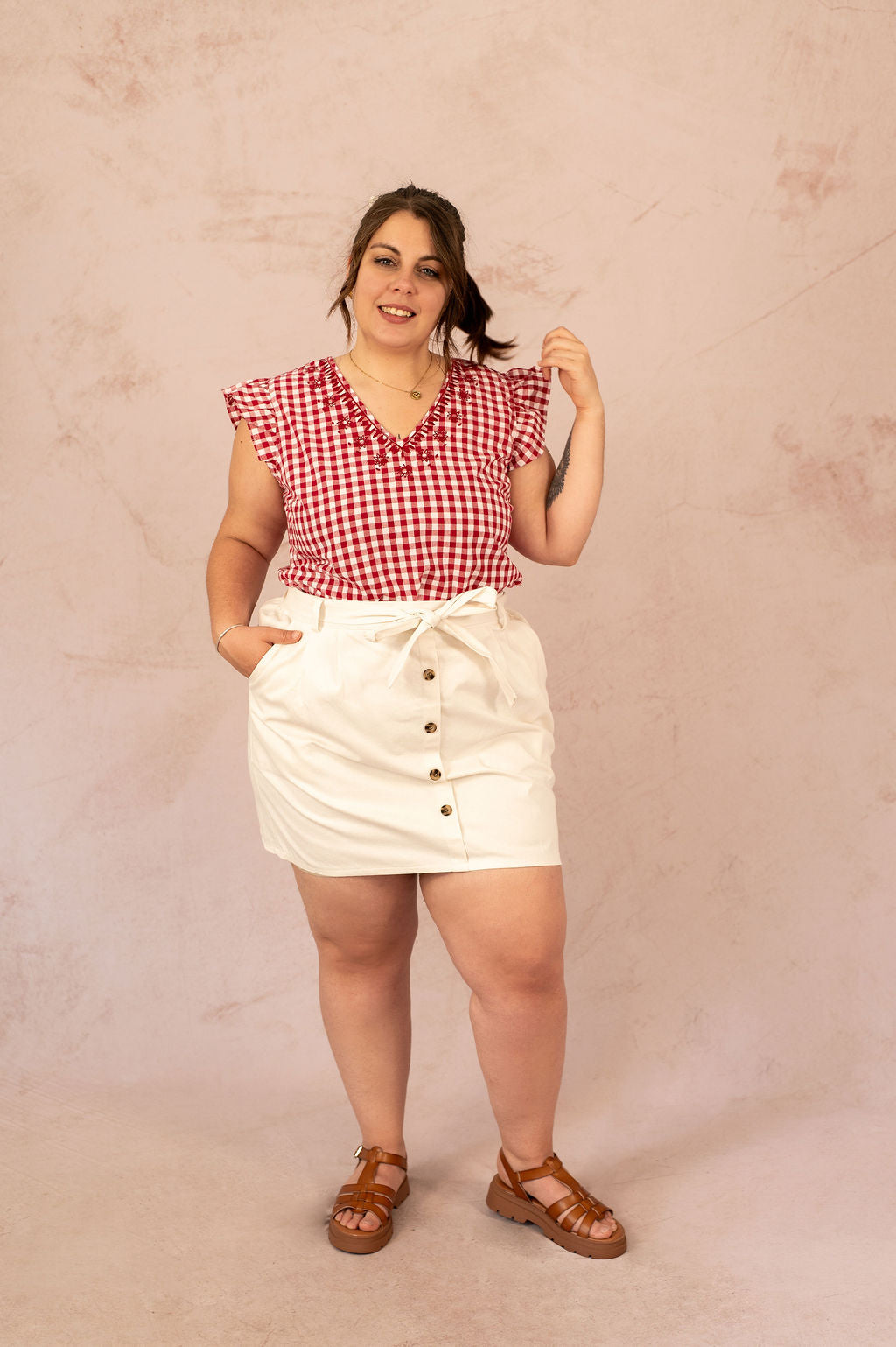 Femme portant la jupe Manon écrue avec boutons et ceinture, tenue estivale grande taille.