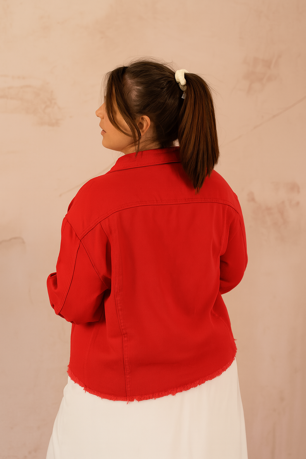 Dos de la veste en jean rouge avec finition frangée sur le bas