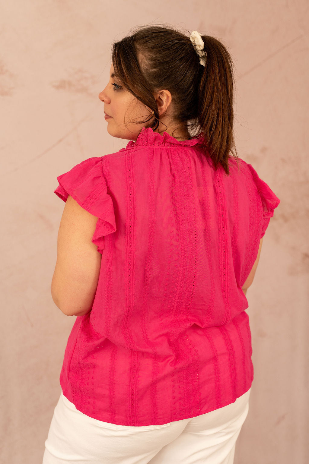 Vue arrière de la blouse Alizée en broderie anglaise rose avec finition légère.