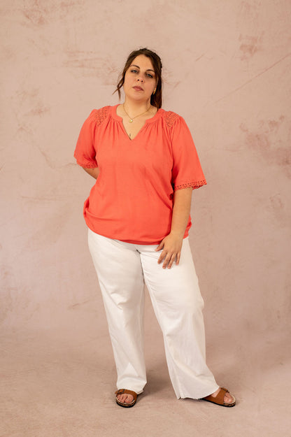 Femme portant une blouse corail avec empiècements en broderie anglaise, vue de face – mode grande taille