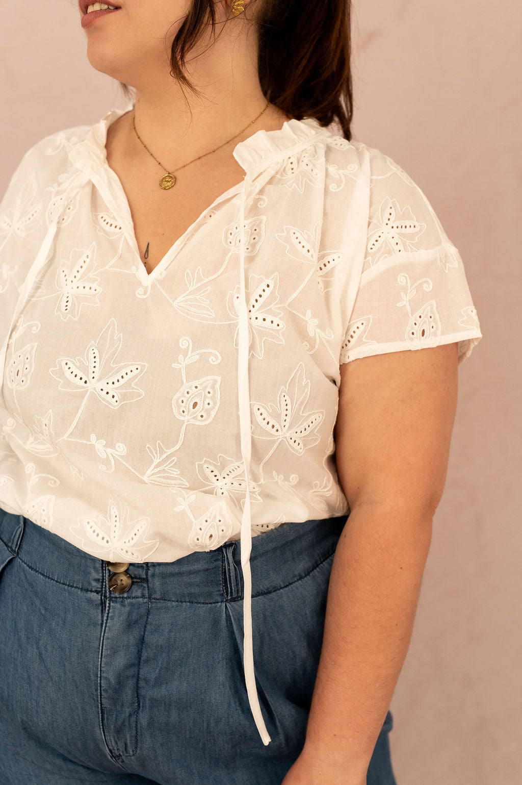 Gros plan sur la blouse Camilla avec broderie anglaise et col volanté avec lien à nouer.