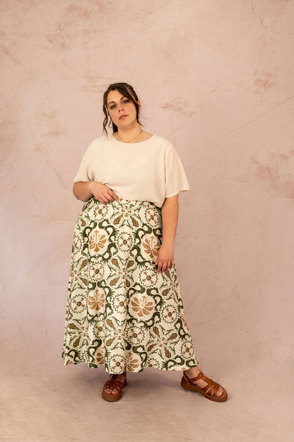 Femme portant la Blouse Vica unie écrue avec une jupe imprimée verte – vue de face