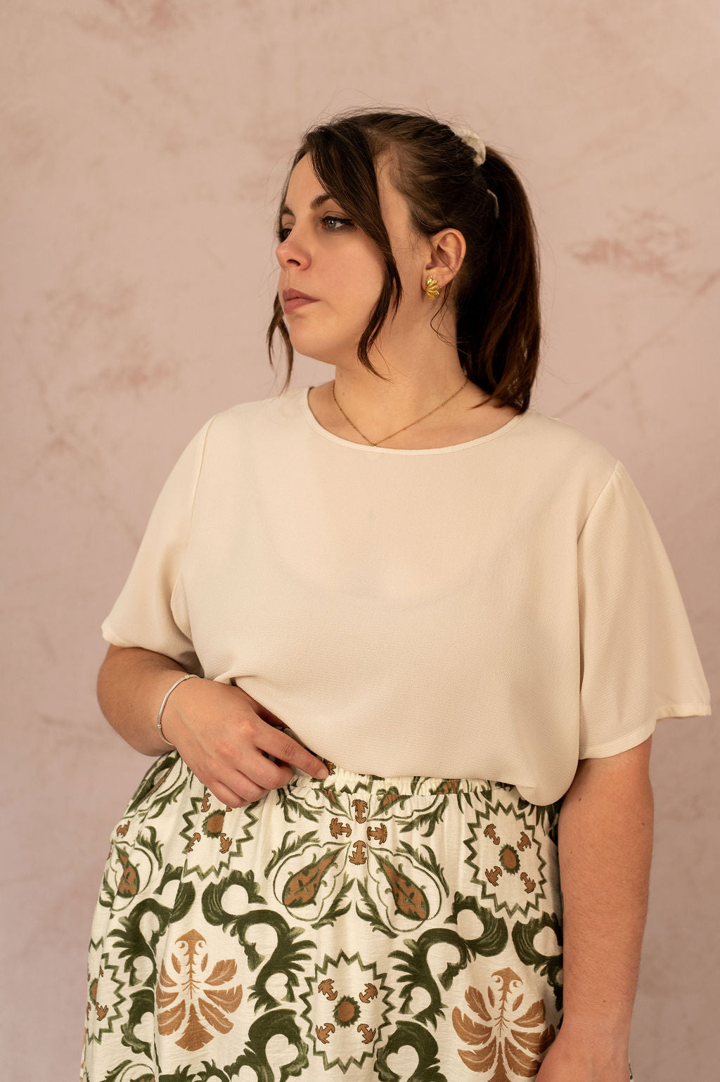 Blouse Vica fluide unie écrue vue de trois-quarts, portée avec une jupe bohème à motifs verts.