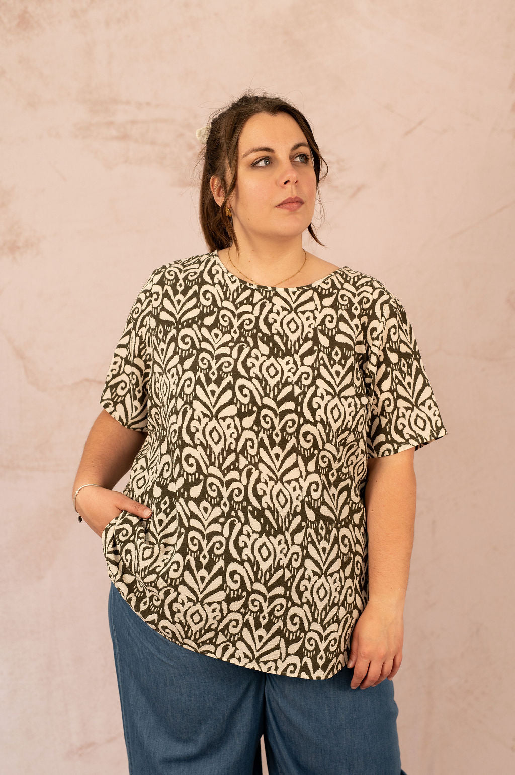 Femme portant la Blouse Vica imprimée kaki et beige avec un pantalon en denim – vue de face.
