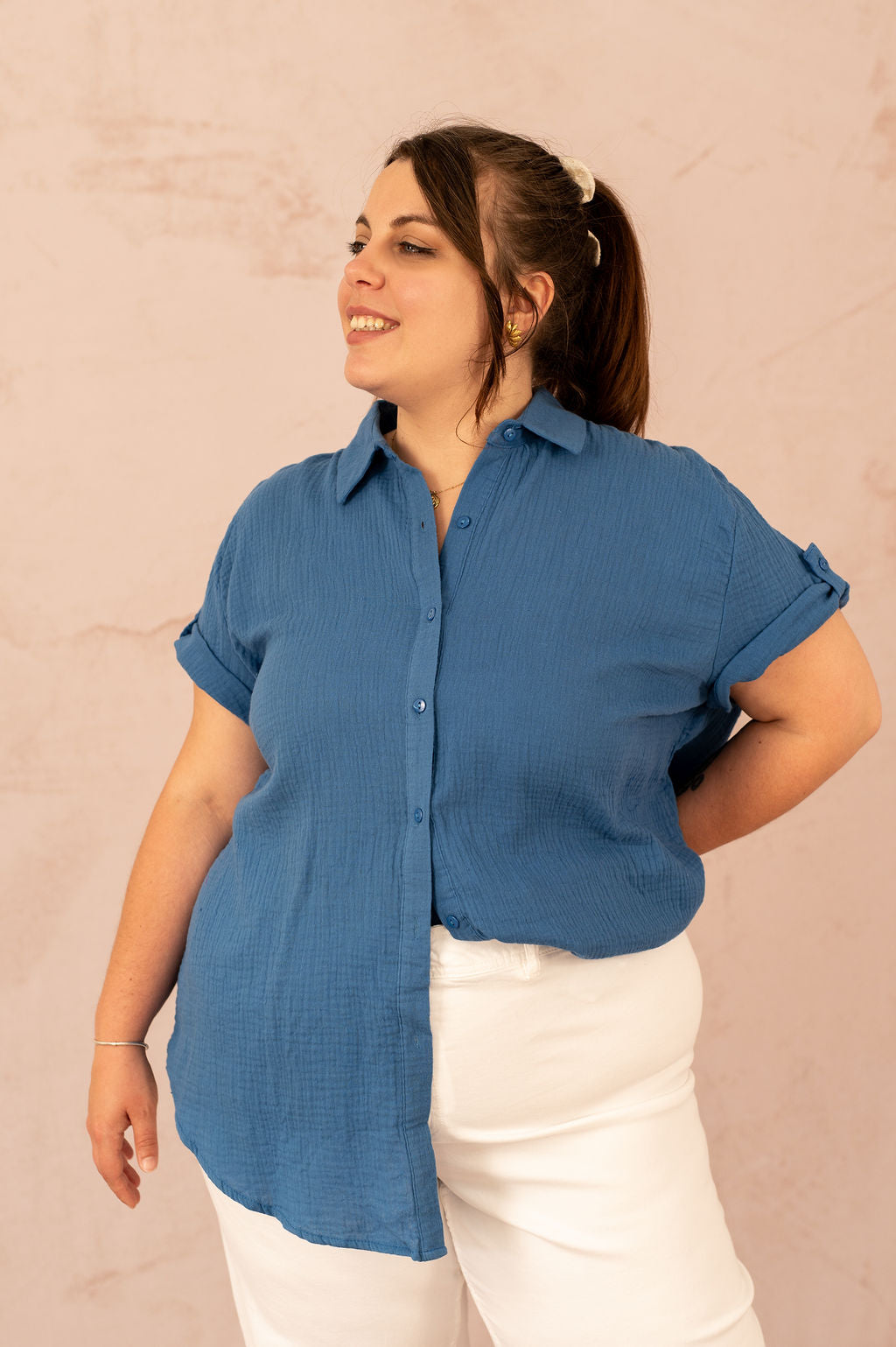 Femme souriante portant une chemise en gaze de coton bleu avec manches retroussées