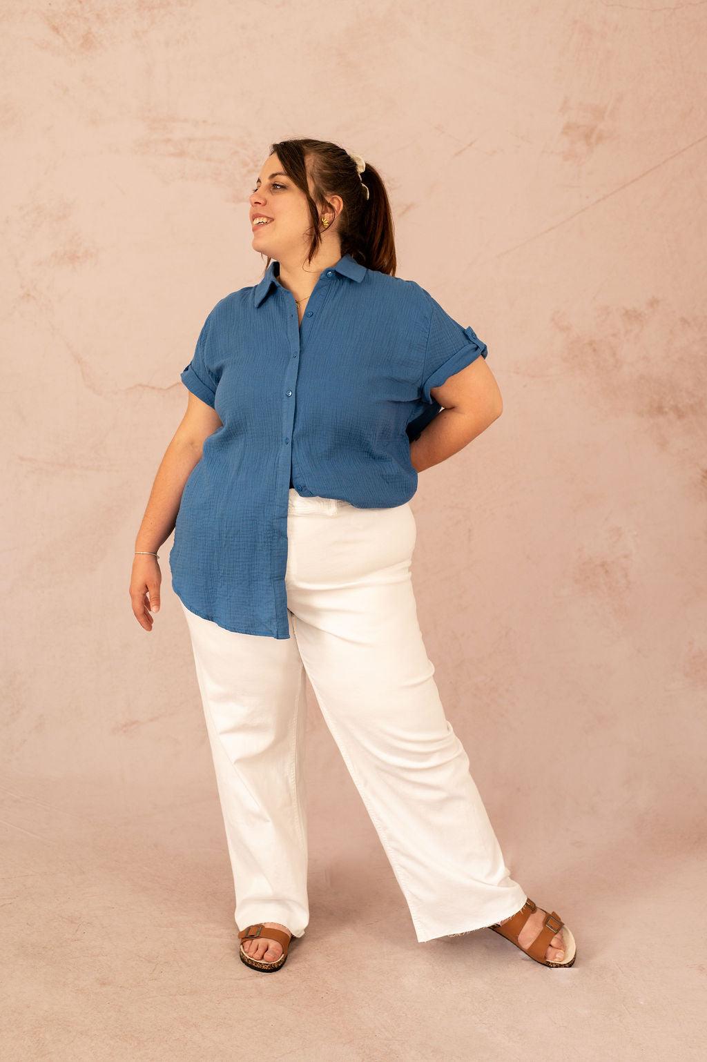 Femme grande taille portant un chemisier bleu en gaze de coton et un pantalon blanc