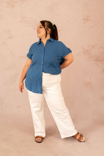 Femme grande taille portant un chemisier bleu en gaze de coton et un pantalon blanc