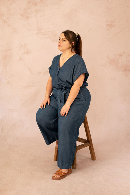 Femme assise portant une combinaison en jean fluide grande taille avec ceinture nouée