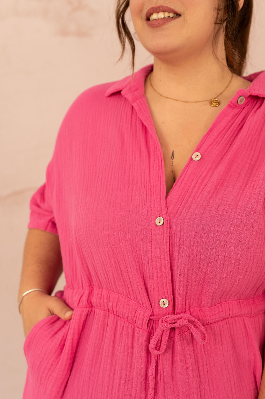 Boutonnage et col ouvert d’un combishort rose en coton gaufré