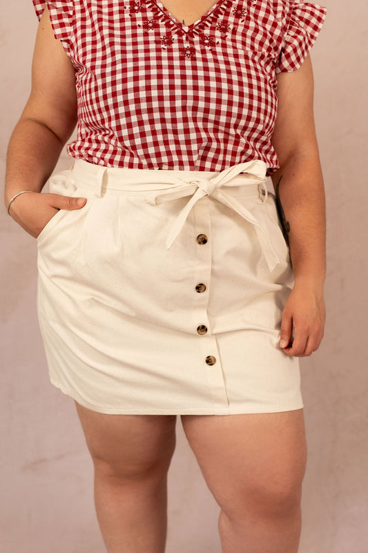 Gros plan sur la jupe Manon, boutons décoratifs et ceinture nouée à la taille.