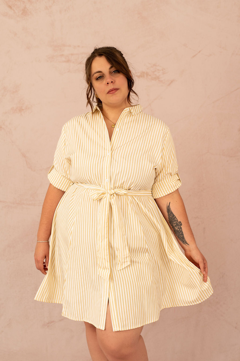 Femme souriante portant une robe chemise rayée jaune avec ceinture nouée à la taille