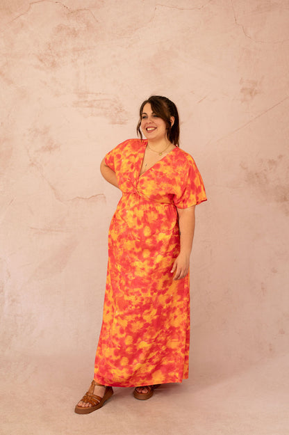 Femme portant la robe longue Ciana coupe empire avec imprimé coloré orange et rose