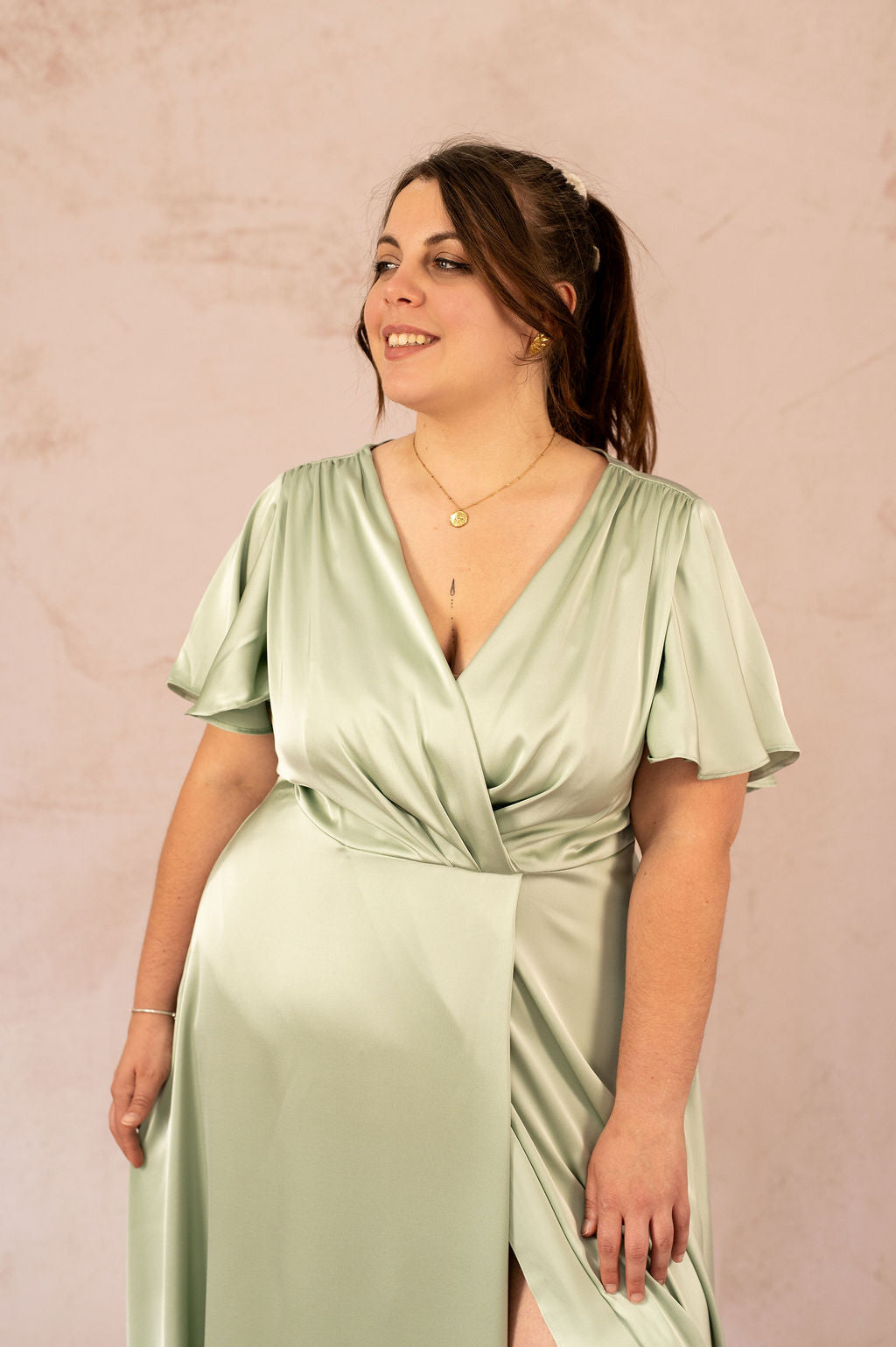 Zoom sur le décolleté croisé et les manches courtes fluides de la robe Luisa en satin vert – Robe cérémonie grande taille
