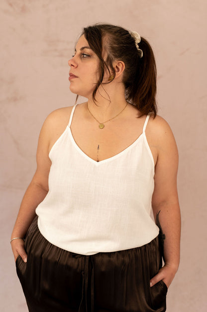 Femme grande taille portant un top blanc fluide avec col V et bretelles fines