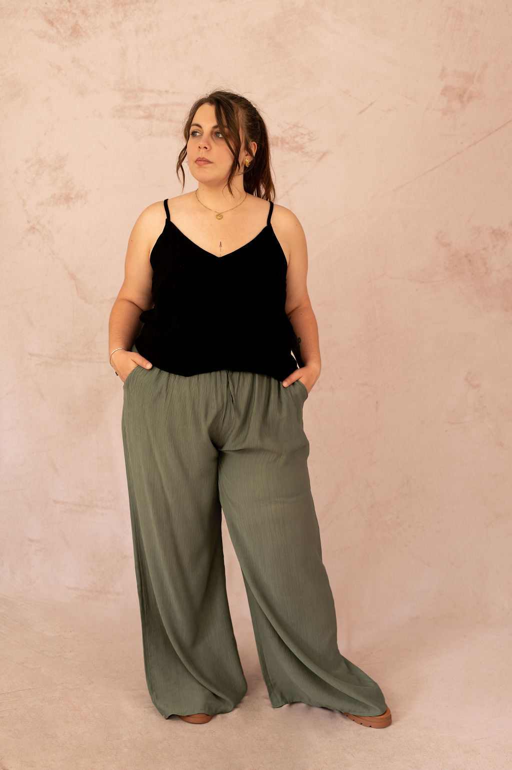Femme grande taille portant un top noir avec dentelle dans le dos et un pantalon fluide kaki