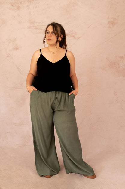 Femme grande taille portant un top noir avec dentelle dans le dos et un pantalon fluide kaki