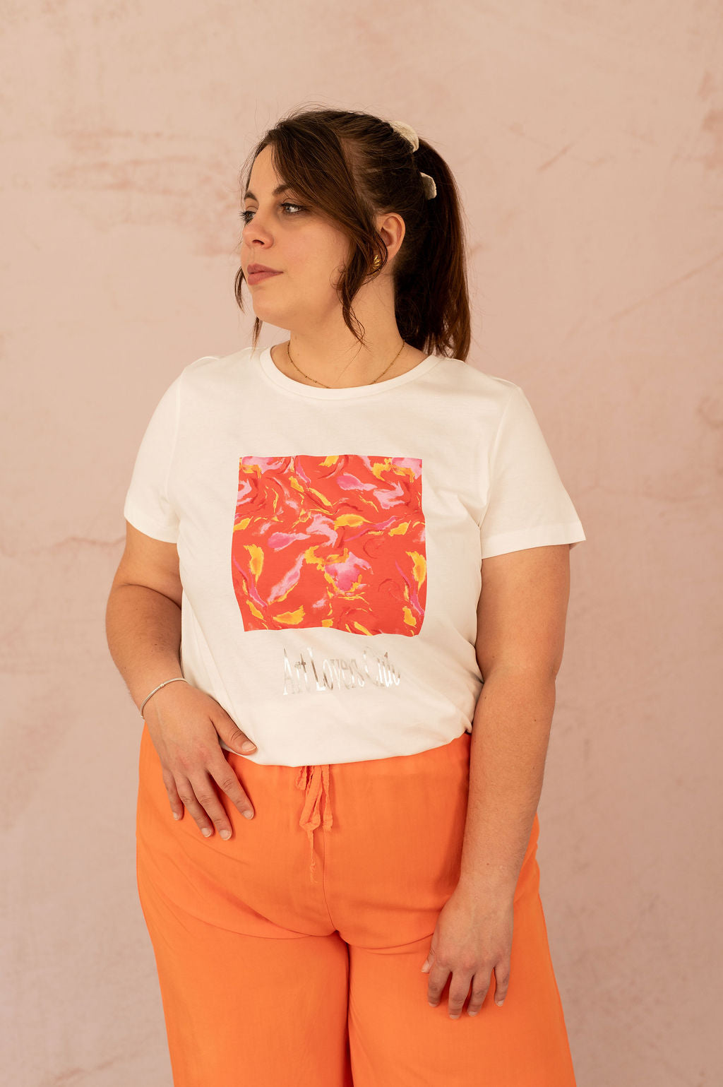 Femme portant un t-shirt blanc avec imprimé artistique orange et rose, vue de face – mode grande taille